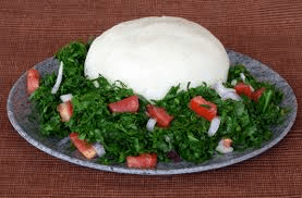 A serving of ugali with sukumawiki on a traditional Kenyan plate