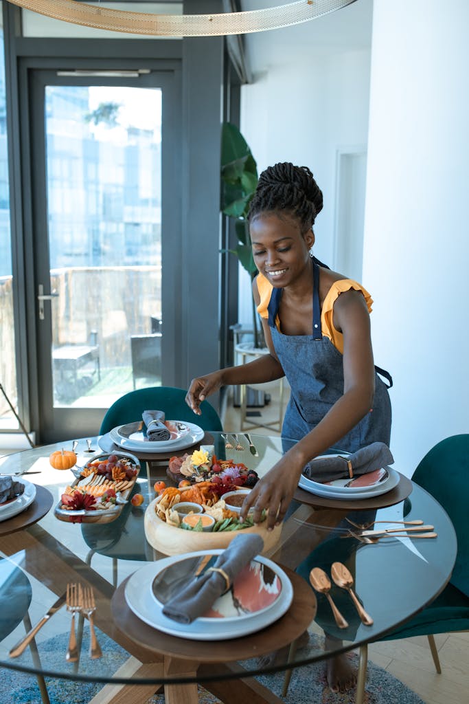 Smiling woman arranging a table with a homemade meal indoors.